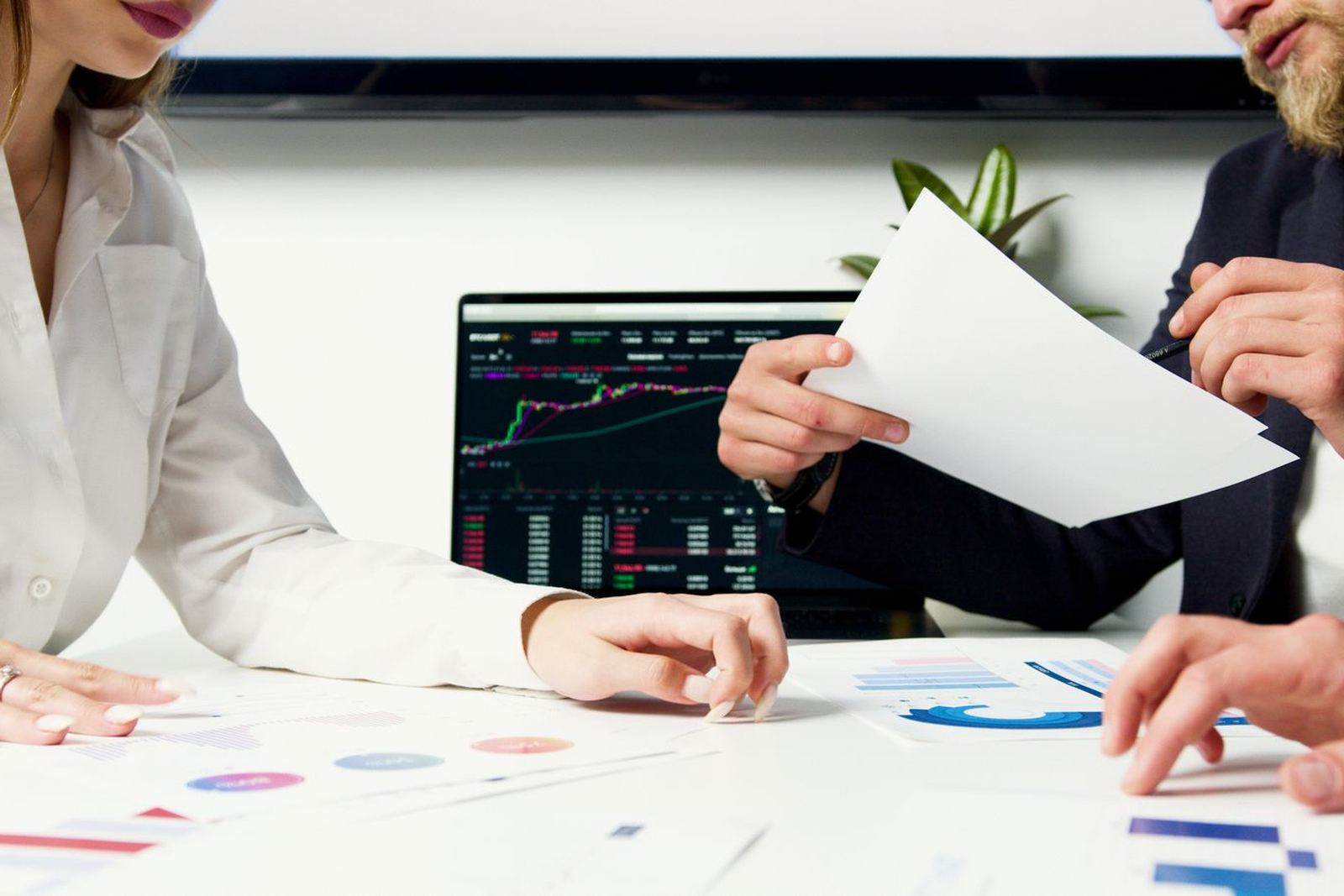 Colleagues analysing data charts on a laptop with printed documents