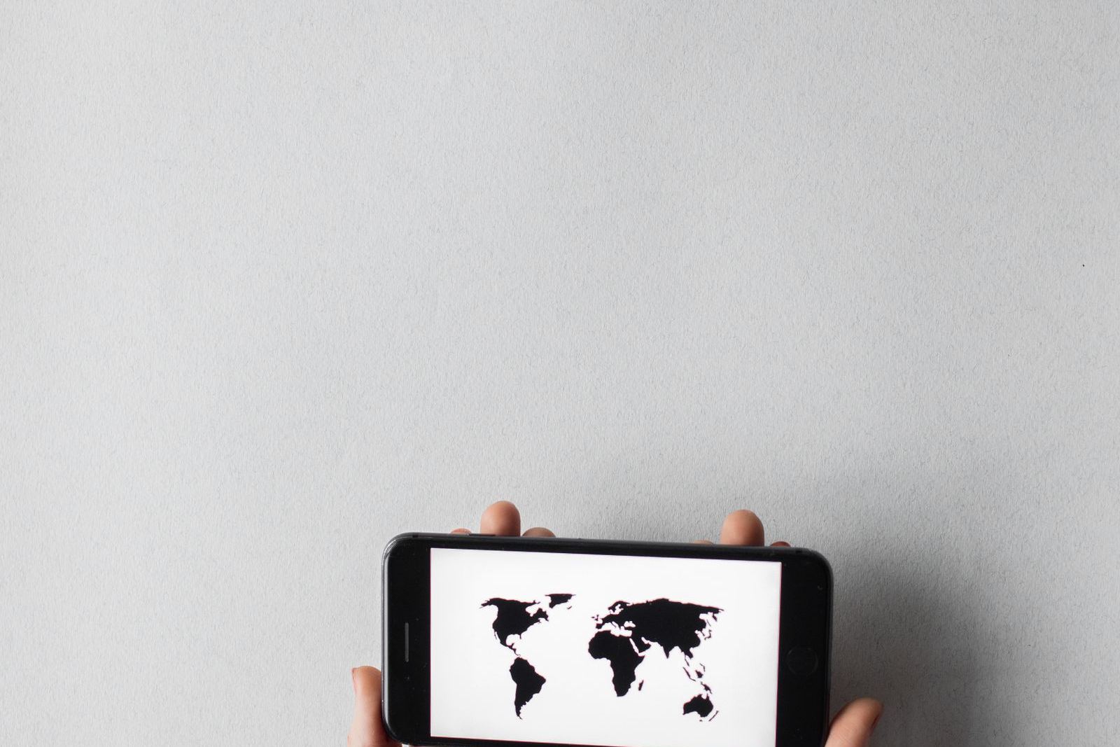 Hands holding a smartphone displaying a world map