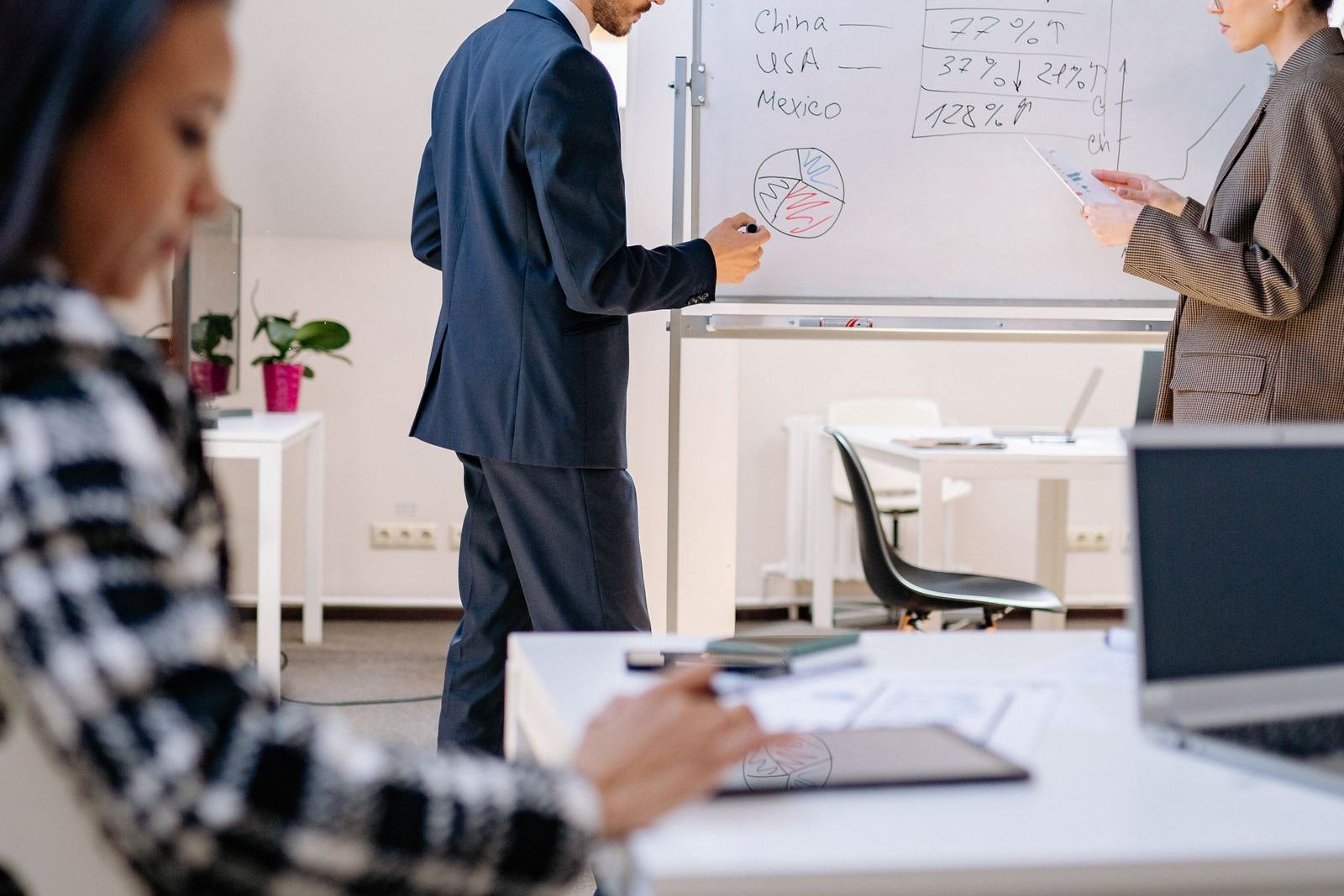 Business colleagues reviewing data at a whiteboard in a modern office